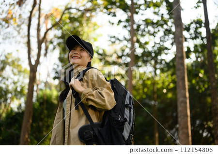 Relaxed young woman with backpack trekking in forest and enjoying nature Relaxed young woman with backpack trekking in forest and enjoying nature 112154806