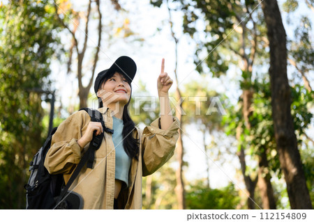 Low angle view of happy young woman trekking in forest and enjoying nature 112154809