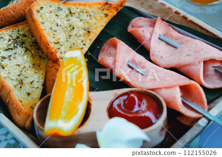 Breakfast with toast bread and ham on wooden tray Breakfast with toast bread and ham on wooden tray 112155026