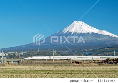 Tokaido Shinkansen N700s passing by winter-dead rice fields with Mt. Fuji in the background 112155862