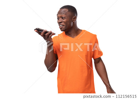 young american man in orange t-shirt speaks on the speaker phone young american man in orange t-shirt speaks on the speaker phone 112156515