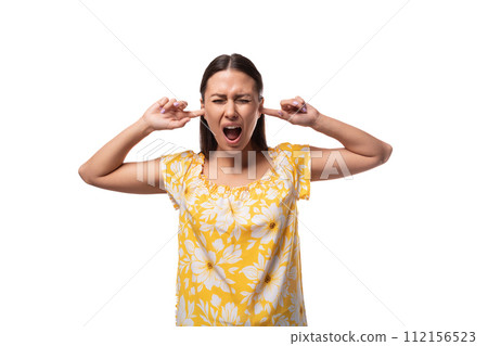 brunette young woman dressed in a summer yellow outfit covered her ears and screams brunette young woman dressed in a summer yellow outfit covered her ears and screams 112156523