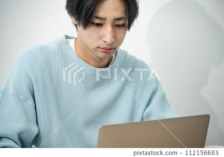 在客廳用電腦工作的年輕人 在客廳用電腦工作的年輕人 112156683