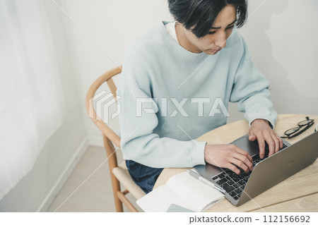 Young man working on a computer in the living room Young man working on a computer in the living room 112156692