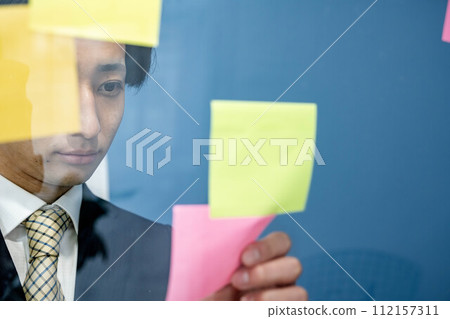 一個穿西裝的年輕人試圖用便條紙組織他的想法 112157311