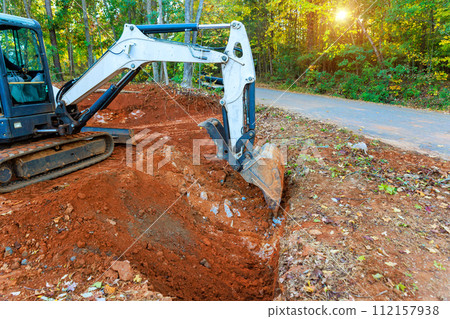 During construction of collection system, an excavator digs trench in which pipe will be laid for flow of rainwater 112157938