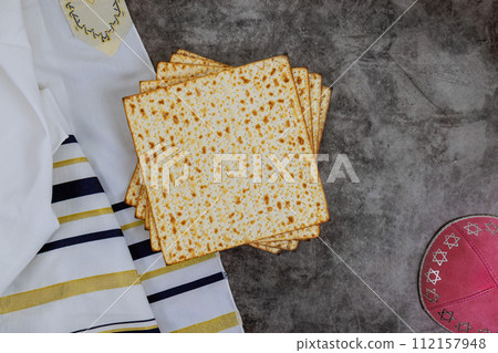 Tradition of Jewish people with Matzah, Passover unleavened bread, kippah, tallit are symbols of Pesach celebration. 112157948