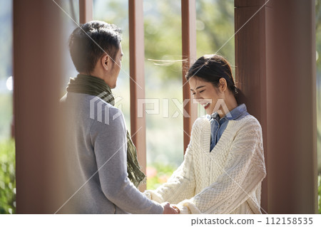 young asian couple talking chatting outdoors in city park young asian couple talking chatting outdoors in city park 112158535