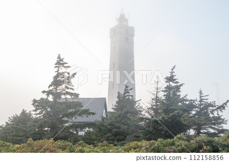 Lighthouse in the sand dunes on the beach of Blavand in fog, Jutland Denmark Europe. 112158856