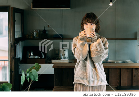 Woman drinking a hot drink at the counter 112159386