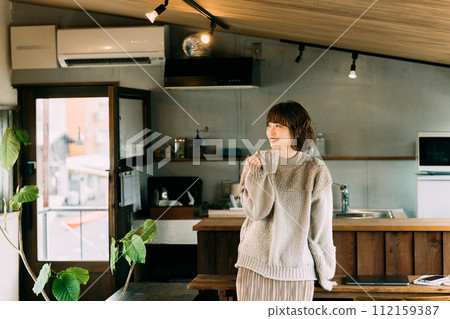 Smiling woman drinking hot drink at counter 112159387