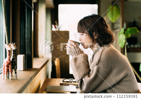 微笑的女人在櫃檯喝熱飲 微笑的女人在櫃檯喝熱飲 112159391