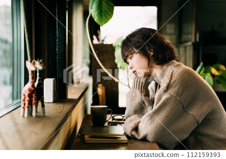 A woman thinking at the counter by the window 112159393