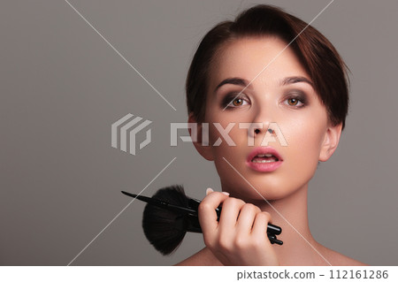 Portrait of a girl with cosmetic brush near face 112161286
