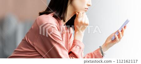 Business woman looking at smartphone and thinking Business woman looking at smartphone and thinking 112162117
