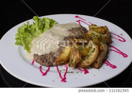 Beautiful and healthy food on a white plate. Fried meat, poured with sauce, French fries with dill, green salad. Fried meat and French fries 112162365