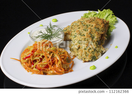 Fried meat in breadcrumbs with stewed carrots and sauce.Eating in a plate. Meat in breading. Fried meat in breadcrumbs with stewed carrots and sauce.Eating in a plate. Meat in breading. 112162366