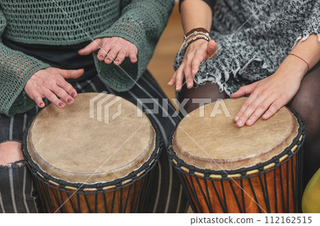 Group of people playing drums during a music therapy lessons, jembe drum, drumming concept Group of people playing drums during a music therapy lessons, jembe drum, drumming concept 112162515