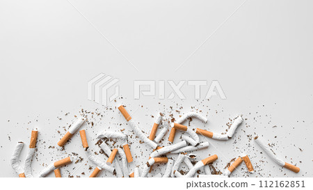 Discarded crushed broken cigarettes and scattered tobacco on white background, representing cessation and the end of smoking with copy space. No tobacco day. 112162851
