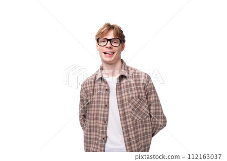 a young smiling man with red golden hair in glasses and a shirt stands alone on a white background a young smiling man with red golden hair in glasses and a shirt stands alone on a white background 112163037