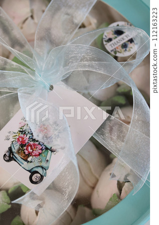 Zephyr in a box. Marshmallow tulips. The box is tied with a ribbon. Close-up. 112163223