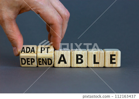 Adaptable or dependable symbol. Businessman turns wooden cubes and changes the word dependable to adaptable. Beautiful grey background, copy space. Business and adaptable or dependable concept. Adaptable or dependable symbol. Businessman turns wooden cubes and changes the word dependable to adaptable. Beautiful grey background, copy space. Business and adaptable or dependable concept. 112163437