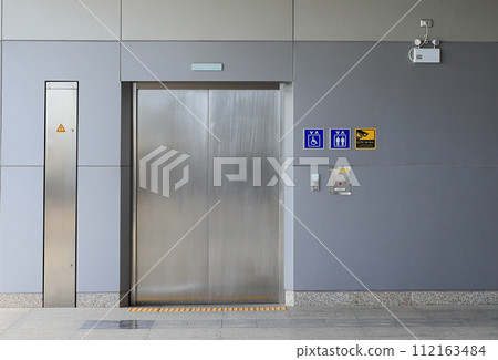 Hallway with LCD screen floor stand, Modern steel elevator cabins, closed elevator doors. Hallway with LCD screen floor stand, Modern steel elevator cabins, closed elevator doors. 112163484