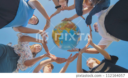 Young friends surround the globe of the world with their palms. The concept of preserving world peace. 112164057