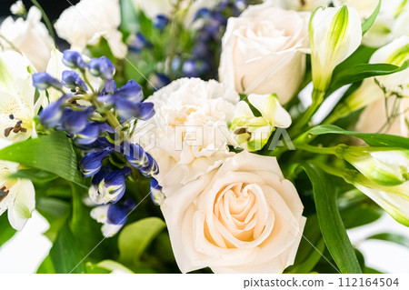 A stunning bouquet featuring fresh white roses and assorted flowers gracefully arranged in a vase, exuding timeless beauty. A stunning bouquet featuring fresh white roses and assorted flowers gracefully arranged in a vase, exuding timeless beauty. 112164504