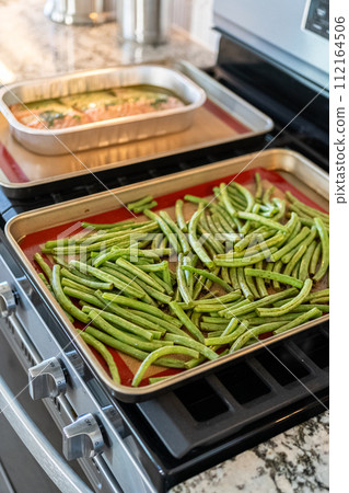 Watch as fresh green beans are beautifully roasted to perfection on a baking sheet with a silicone mat, adding a burst of flavor to your meal. 112164506