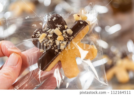 Carefully packaging Christmas cutout cookies, half-dipped in chocolate and presented in clear cellophane wrapping, perfect for festive gifting. Carefully packaging Christmas cutout cookies, half-dipped in chocolate and presented in clear cellophane wrapping, perfect for festive gifting. 112164511
