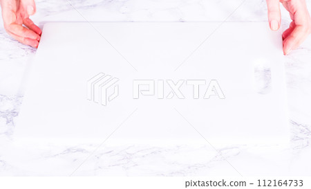 Succulent red strawberries, some showing early spoilage, are arrayed on a white cutting board, held securely in place, with a paper towel lined glass bowl nearby suggesting an attempt at preservation. 112164733