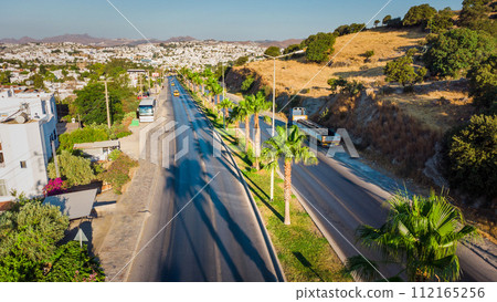 Road in tropical city. Landscape with rocks, sunny sky with clouds and beautiful asphalt road in the evening in summer.Travel background. Transportation 112165256