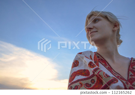 Stylish girl relaxing in summer. Young woman dreaming on blue sky background. Stylish girl relaxing in summer. Young woman dreaming on blue sky background. 112165262