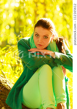Sad woman sitting in green forest park 112165612