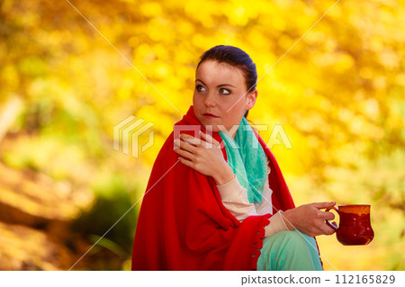 thoughtful girl in the autumn park enjoying hot drink 112165829