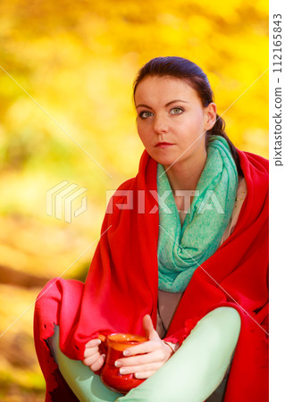 thoughtful girl in the autumn park enjoying hot drink 112165843