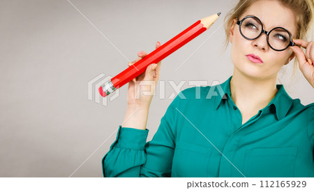 Woman confused thinking, big pencil in hand Woman confused thinking, big pencil in hand 112165929