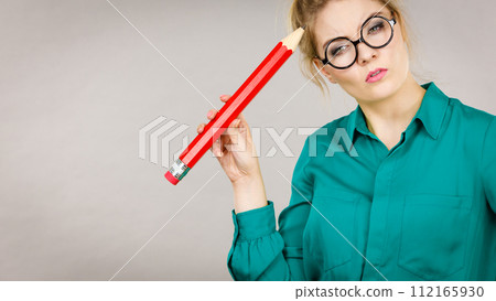 Woman confused thinking, big pencil in hand Woman confused thinking, big pencil in hand 112165930