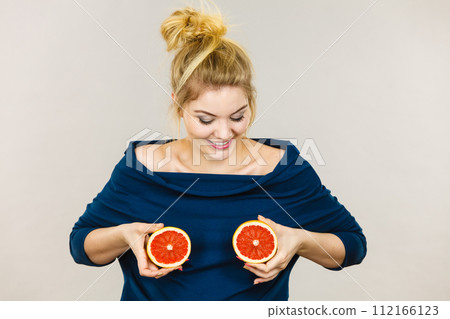 Woman holding red grapefruit on breast 112166123