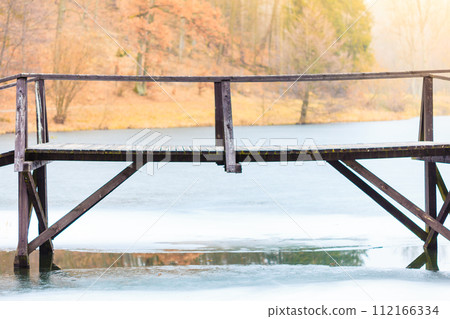 Old, wooden, small bridge on frozen lake 112166334