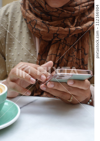 women hand holding smart phone sitting on cafe  112166984