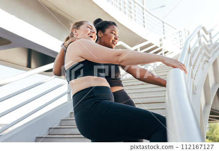 Two sportswomen having fun while standing at railing on the bridge after an intense workout. Female friends in sportswear enjoying a good mood after exercises. 112167127