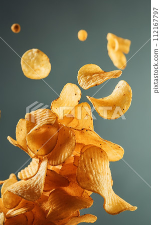 Crispy and crunchy golden potato chips on a bokeh light background. Crispy and crunchy golden potato chips on a bokeh light background. 112167797