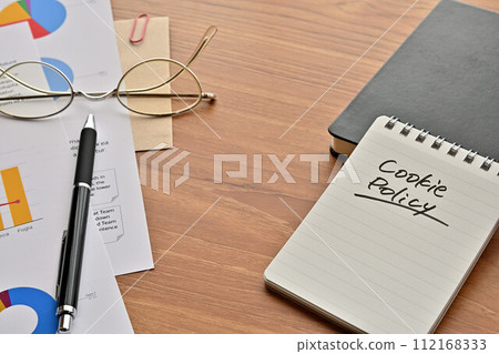 A desk with a notepad that says Cookie Policy, glasses, and a pen 112168333