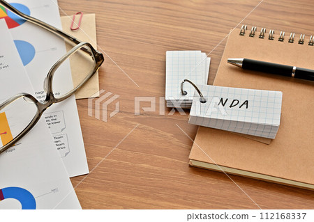 A desk with a vocabulary book with NDA written on it, glasses and a pen 112168337