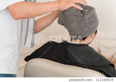 A female customer and stylist/hairdresser shampooing on a shampoo table in a beauty salon (salon shampoo) 112169024