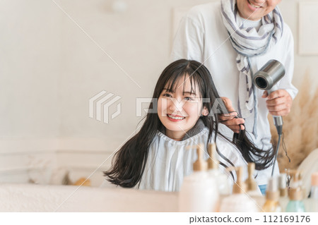 Stylist/hairdresser and female customer drying hair with a hair dryer Stylist/hairdresser and female customer drying hair with a hair dryer 112169176