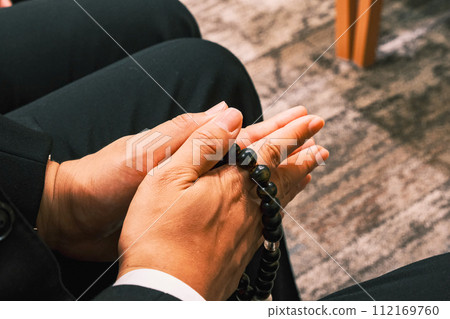 [#Funeral] A man's hand holding a rosary 112169760