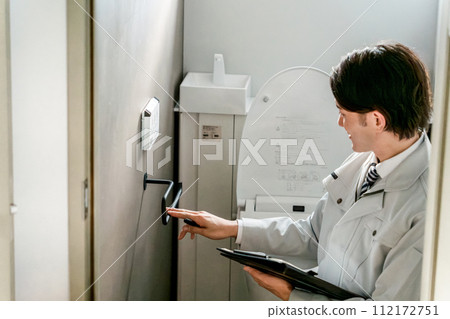 一名穿著水管工/設備店衣服的男子檢查廁所裡的毛巾架 112172751